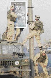 Soldiers with the U.S. Army's 101st Airborne Division hang up a panel on a street in Mosul on Saturday calling for Iraqis to cooperate.